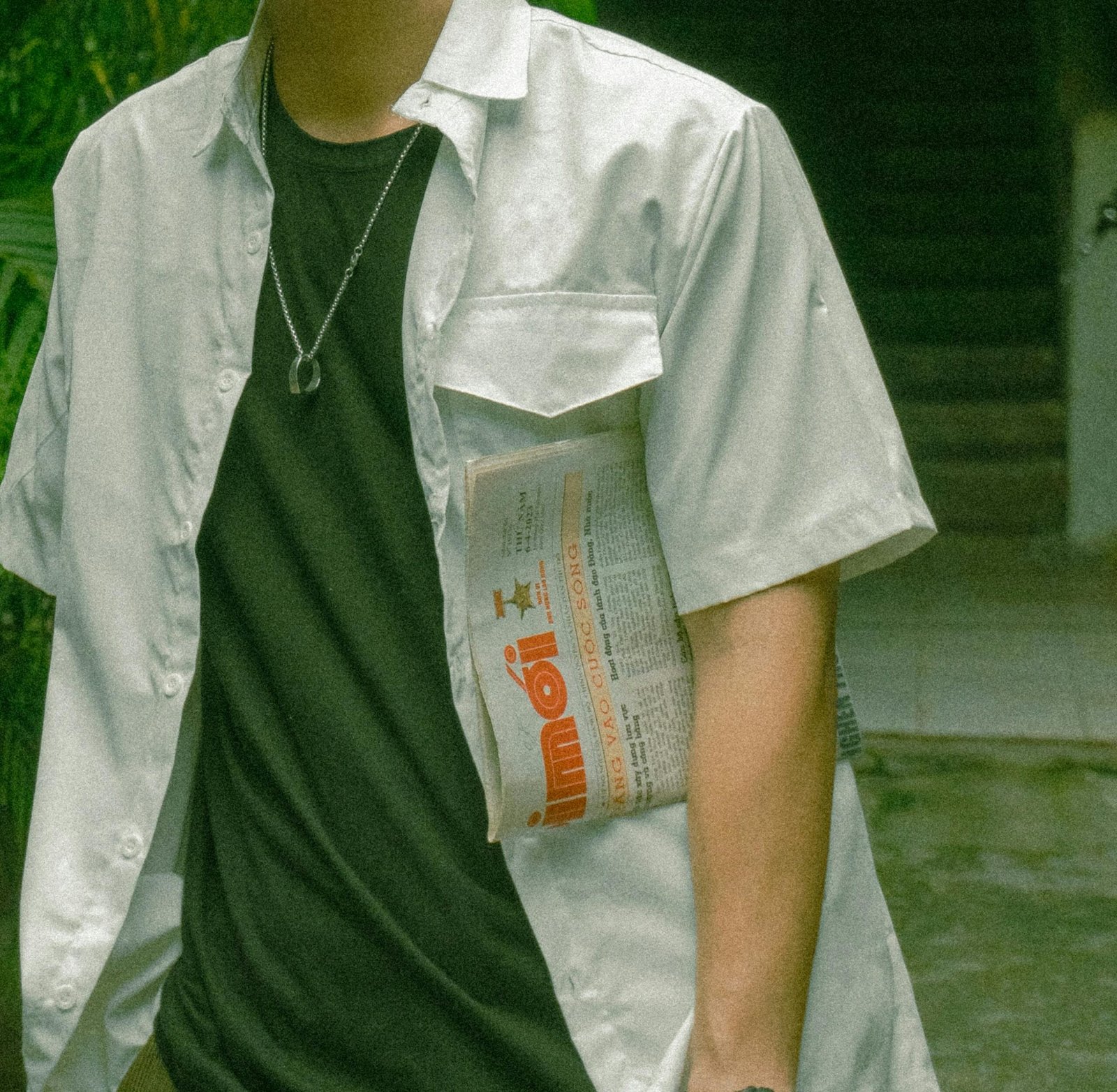 Young Man in a White Shirt Holding a Newspaper