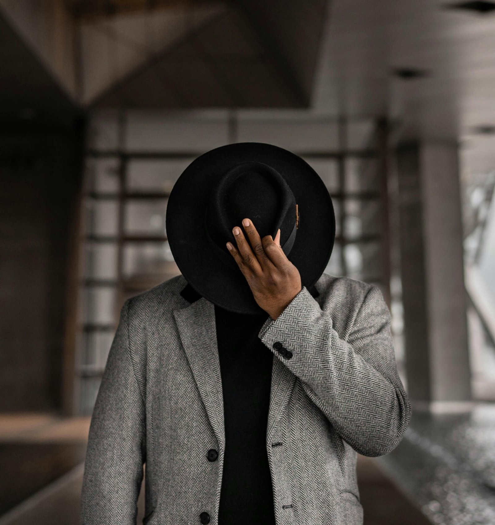 Person in Gray Coat Holding Black Hat